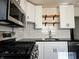 Updated kitchen features black appliances, white cabinets, open shelves and subway tile backsplash at 212 S Good Ave, Indianapolis, IN 46219