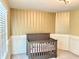 This is a Bedroom featuring a crib with a gray frame, striped wall paper and wainscoting at 5778 W Commonview Dr, McCordsville, IN 46055