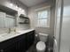 Bathroom featuring a vanity, toilet, and mirror with modern lighting and decorative shelves at 839 Fernwood Ct, Indianapolis, IN 46234