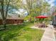Spacious backyard with a wooden fence, patio furniture under a red umbrella, and mature trees at 104 W County Road 500 S, Clayton, IN 46118