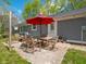 Cozy outdoor patio with dining set, accented by string lights, and shaded by a vibrant red umbrella at 104 W County Road 500 S, Clayton, IN 46118