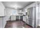 Well-lit kitchen featuring stainless steel appliances, white cabinetry and backsplash, and dark hardwood flooring at 1829 New St, Indianapolis, IN 46203