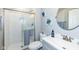 Bathroom with stand-up shower with glass doors, toilet, sink, round mirror and blue accents at 8528 Quail Hollow Rd, Indianapolis, IN 46260
