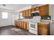 Well-lit kitchen featuring wood cabinets, white appliances, tile backsplash, and durable flooring at 825 Arrow Ave, Anderson, IN 46016