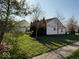 View of a side yard with green grass and various trees, with other homes visible in background at 8010 Philadelphia Dr, Fishers, IN 46038