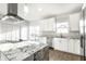 Bright kitchen featuring white cabinets, stainless steel appliances, a vent hood, and a large center island with granite countertops at 1015 Churchman Ave, Indianapolis, IN 46203