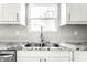 Close-up of kitchen sink with stainless steel faucet, granite countertops, and white cabinets at 1015 Churchman Ave, Indianapolis, IN 46203