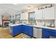 Bright kitchen featuring colorful blue cabinetry, stainless appliances, and a view of an adjacent dining area and fireplace at 5707 Kensington Blvd, Plainfield, IN 46168