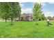 Expansive green lawn showcasing the home's exterior with mature trees and manicured landscaping at 5707 Kensington Blvd, Plainfield, IN 46168