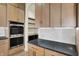 Close up of kitchen showing double oven, light wood cabinets, dark countertops and backsplash at 5469 Harness Dr, Greenwood, IN 46143