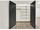 A generous walk-in closet with white shelves and wood floors, accessible through sleek, dark-colored doors at 5469 Harness Dr, Greenwood, IN 46143