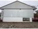 View of garage wall displaying window and white-painted brick foundation and metal siding at 5625 Gateway Dr, Indianapolis, IN 46254