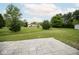 Expansive backyard with lush green grass, mature trees, and a neutral colored paver patio at 975 Red Hills Ct, Lebanon, IN 46052