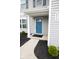 Close-up view of front entrance with blue door, white trim, a small garden, and house number at 975 Red Hills Ct, Lebanon, IN 46052