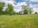 Beautifully landscaped front yard with lush green lawn and mature trees creating a serene and inviting curb appeal at 5784 N 600 E, Greenfield, IN 46140