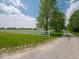 Spacious yard featuring a white fence, mature trees, and a gravel driveway leading to the property at 5784 N 600 E, Greenfield, IN 46140