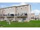 Back exterior view of townhome with balconies and a well-manicured lawn at 7282 Zanesville Rd, Carmel, IN 46033