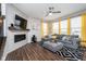 Cozy living room with fireplace, TV, large grey sofa, modern rug and bright yellow curtains at 7282 Zanesville Rd, Carmel, IN 46033