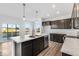 A modern kitchen with an island, stone countertops, stainless steel appliances, and hardwood floors at 908 Stonehaven Dr, Indianapolis, IN 46239