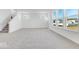 A large living room with many windows, carpet, and a view to the stairs at 908 Stonehaven Dr, Indianapolis, IN 46239