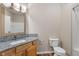 Bathroom featuring a granite countertop, wood cabinets, toilet, mirror and shower at 12820 University Cres # 2D, Carmel, IN 46032