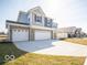 Side view of a two-story home with a three-car garage and newly seeded lawn in a suburban neighborhood at 287 Lar Lan Dr, Danville, IN 46122