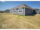 View of home's gray exterior and backyard, showing green grass and sunny skies at 301 Lar Lan Dr, Danville, IN 46122