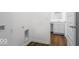 Bright laundry room with white walls and dark wood-look floors adjacent to bathroom with white vanity at 9344 Anthem Ave, Plainfield, IN 46168