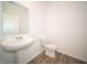 A bathroom features a pedestal sink, toilet, and light gray wood floors at 7904 Magnolia St, New Palestine, IN 46163