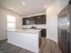 Modern kitchen featuring dark wood cabinets and an island with a stainless fridge at 7904 Magnolia St, New Palestine, IN 46163