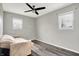 Spacious bedroom with a modern ceiling fan, gray walls, wood-look floors, and two windows for natural light at 8902 Carla Dr, Indianapolis, IN 46219
