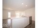 Bright kitchen island featuring a stainless steel sink, white cabinets, and view to a backdoor patio at 6623 Sulgrove Pl, Indianapolis, IN 46221
