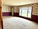 Bright living room with carpeted floors, large window, and floral wallpaper, creating a cozy and inviting atmosphere at 8418 S State Road 39, Clayton, IN 46118