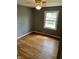 An empty bedroom features hardwood floors, a lighted ceiling fan, neutral paint, and natural light from the window at 927 Stockton St, Indianapolis, IN 46260