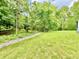 View of the backyard with a dry creek bed, green grass, and mature trees at 7650 Clarion Dr, Indianapolis, IN 46236