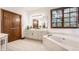 A spacious bathroom showcasing a marble tub, white vanity, and rich, dark wooden doors at 1462 Eagle Trace Ct, Greenwood, IN 46143