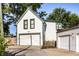 Exterior shot of garage with white siding, green trim, and mature trees, showcasing the property's curb appeal at 545 Fletcher Ave, Indianapolis, IN 46203