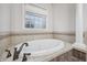 Luxurious soaking tub with tile surround, stylish fixtures, and bright window offering natural light at 1038 White Oak Dr, Plainfield, IN 46168