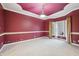 Bright bedroom featuring a red accent wall, tray ceiling, and large window offering ample natural light at 1038 White Oak Dr, Plainfield, IN 46168