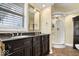 Bathroom featuring a double sink vanity with black countertops, a shower with glass doors, and a large mirror at 2227 Hidden Orchard Ct, Indianapolis, IN 46228