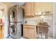 Laundry room with stacked washer and dryer, a stainless steel sink, and natural wood cabinets at 2227 Hidden Orchard Ct, Indianapolis, IN 46228
