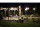 Nighttime view of outdoor pergola featuring overhead lights, stone flooring, plants, and chairs with an inviting atmosphere at 2227 Hidden Orchard Ct, Indianapolis, IN 46228