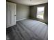 An empty bedroom with a window, neutral walls, carpeted floors, and a white door at 12023 Crestwater Ct, Fishers, IN 46037