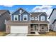 Charming two-story home with blue siding, brick accents, attached two-car garage, and a covered entryway at 7062 English Oak Dr, McCordsville, IN 46055