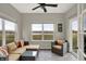 Bright sunroom featuring large windows with lake views, comfortable seating, and a ceiling fan at 7062 English Oak Dr, McCordsville, IN 46055