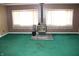 Living room with green carpet, brown walls, and a black wood-burning stove at 406 S Fenton Ave, Indianapolis, IN 46219