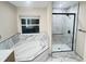 Bathroom featuring a soaking tub with a window view, a walk-in shower, and marble-style tile at 13271 Lorenzo Blvd, Carmel, IN 46074