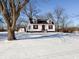 White house with red accents, snowy yard, and detached garage at 4509 Madison Ave, Anderson, IN 46013