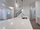 Modern kitchen island with stainless steel sink and pendant lighting, as well as view to staircase and front door at 537 Gilder Dr, Carmel, IN 46032