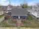 Quaint blue home with a brick porch, gray roof, fenced yard, and small landscaped garden at 323 E Franklin St, Shelbyville, IN 46176